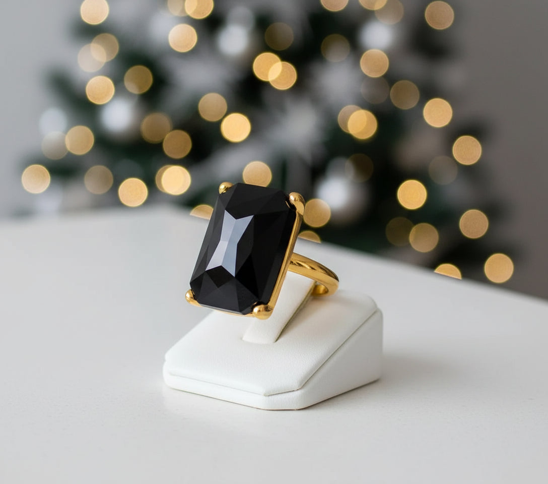 Gold ring with a large black zircon stone on a white background